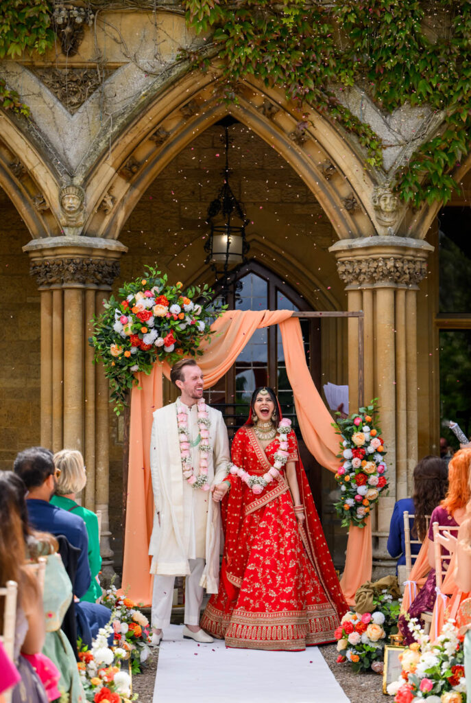Bride and groom standing beneath a floral arch during their Manor by the Lake wedding ceremony.