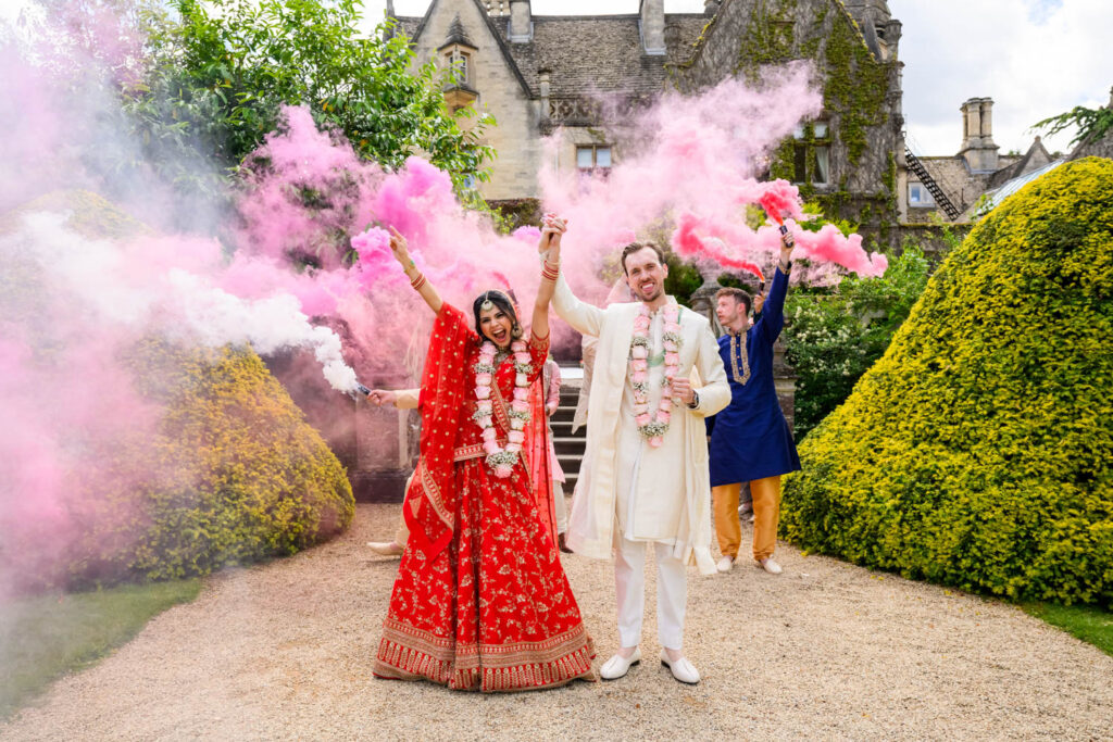 Bride and groom surrounded by pink smoke during colourful Manor by the Lake wedding photography.