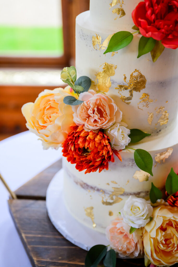Close-up wedding photography of a floral wedding cake with gold leaf details at Manor by the Lake.