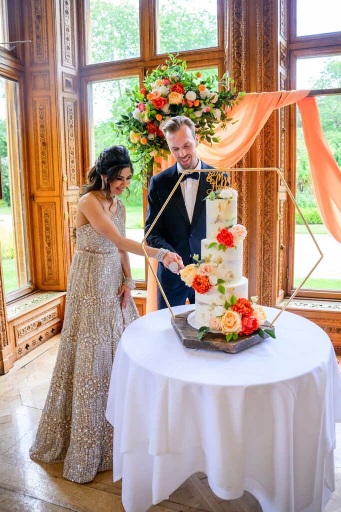Bride and groom cutting their floral wedding cake during wedding reception in the ballroom