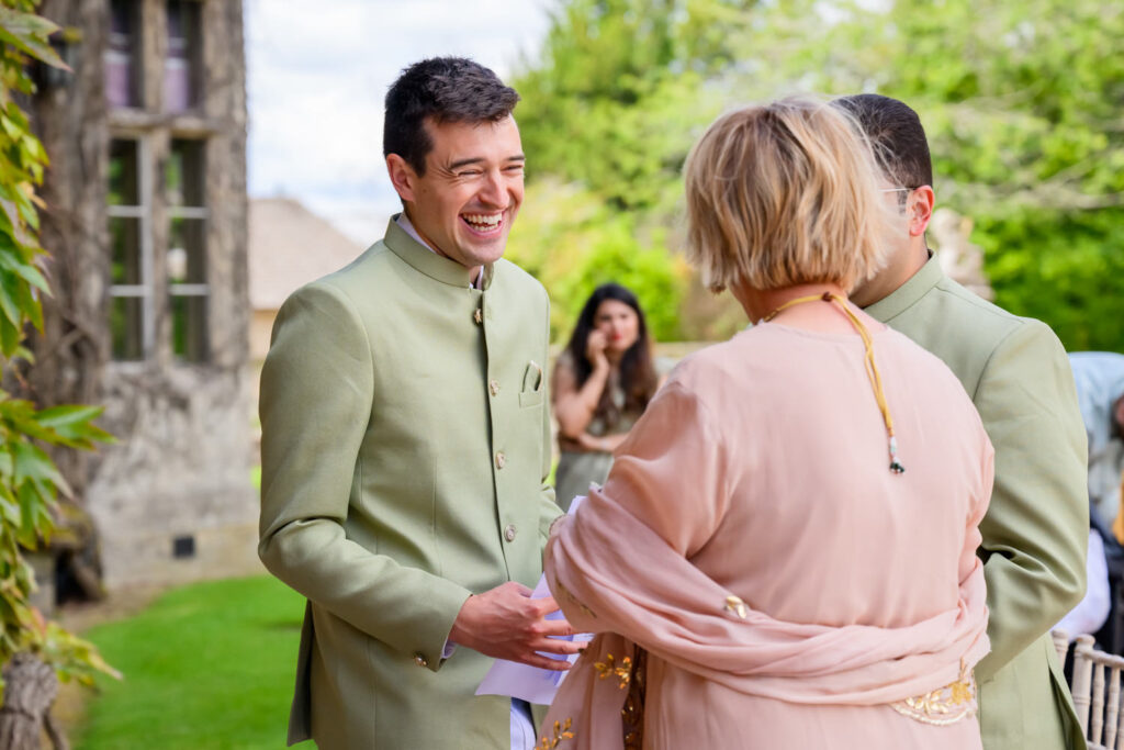 Best man greeting guests in the gardens at Manor by the Lake wedding venue.
