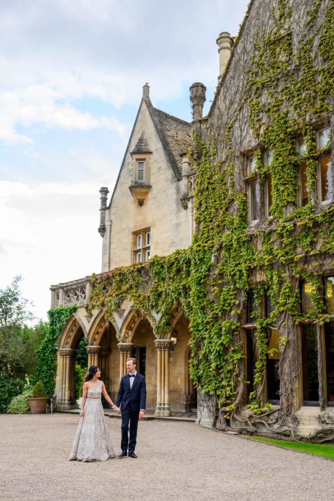 Wide angle wedding portrait of the couple outside the ivy-covered façade of Manor by the Lake.