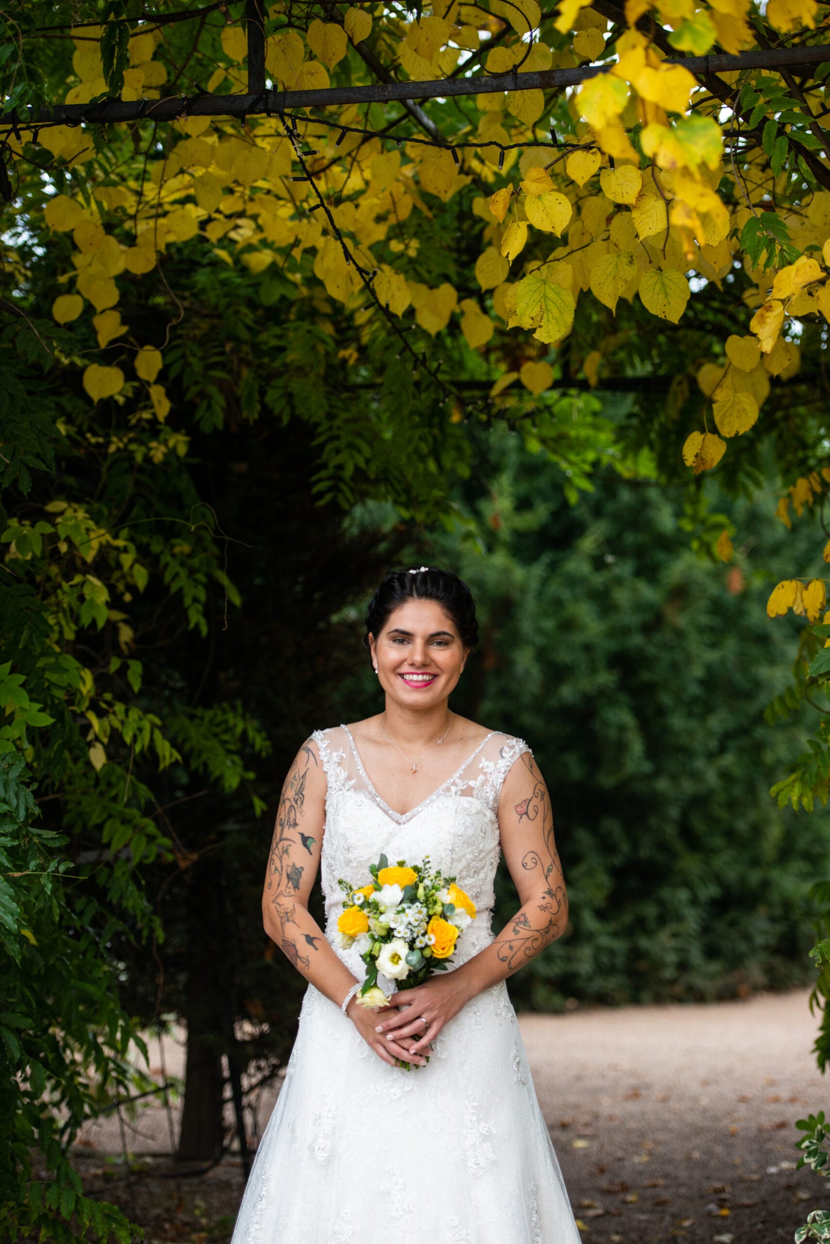 happy bride stood outside under automnal leaves on her wedding day
