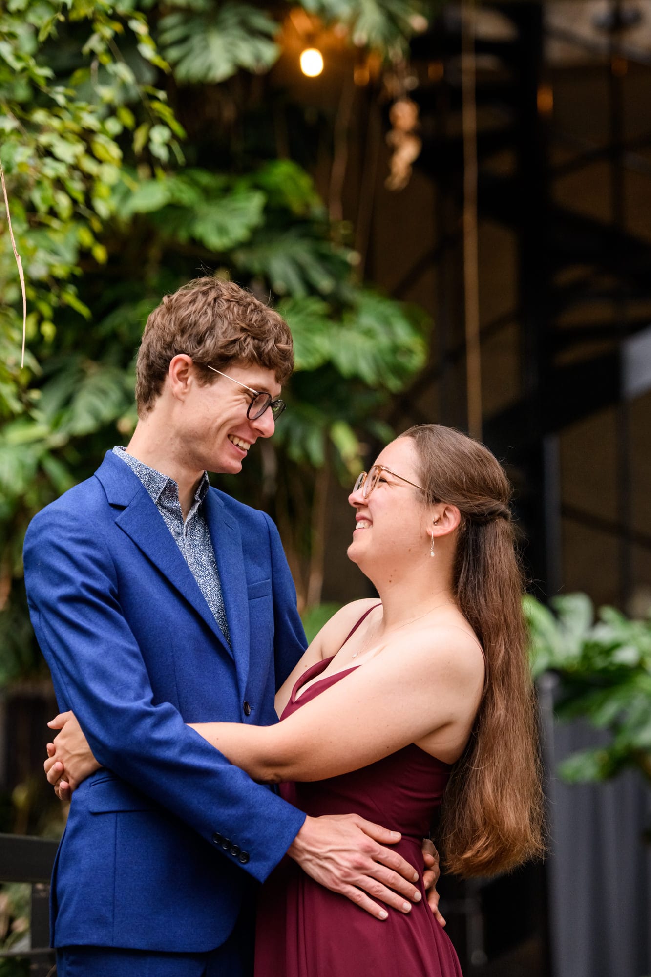happy wedding couple with arms around each other whilst surrounded by plants