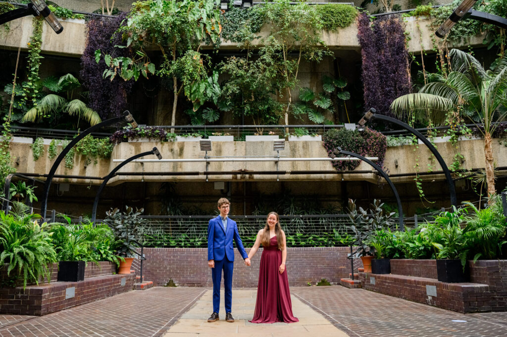 Couple holding hands during engagement photoshoot inside The Barbican Conservatory