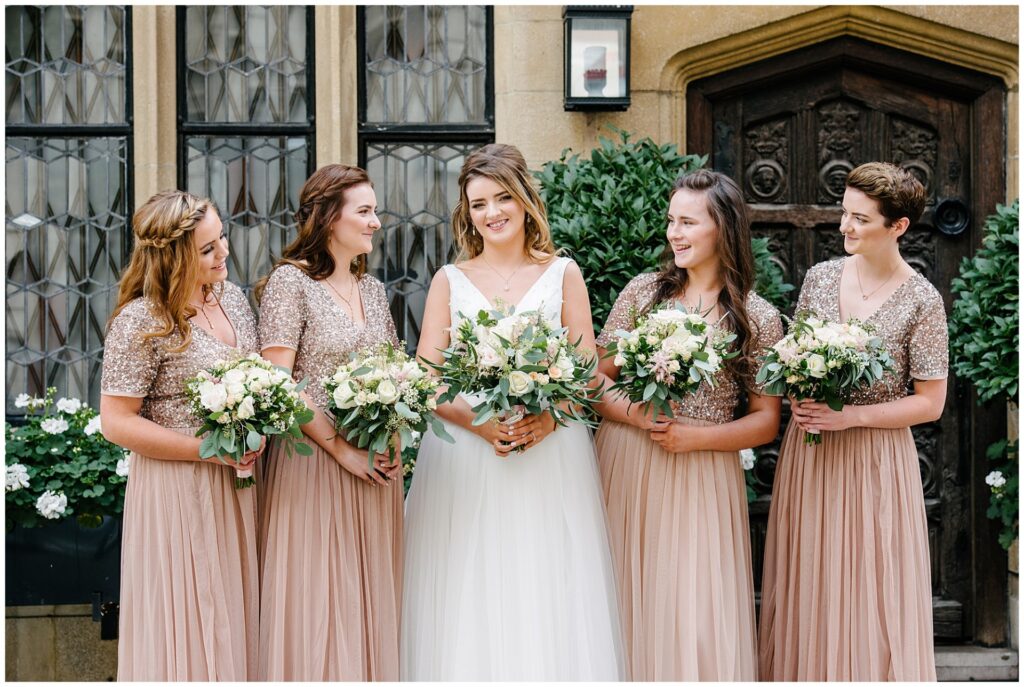 Bride stood laughing with her bridesmaids all wearing peach sequinned dresses in Mayfair