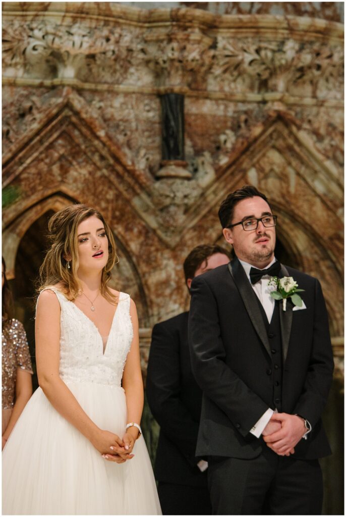 bride and groom singing during wedding ceremony at Farm Street Church in Mayfair