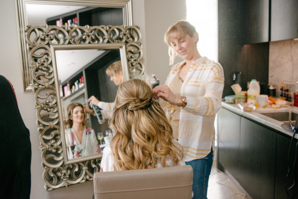 Bride looking into mirror whilst having her hair done on summer wedding day