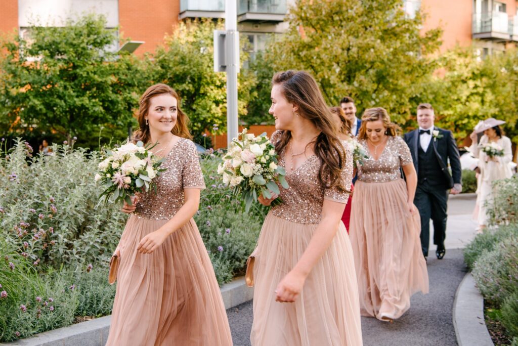 bridesmaid walking and laughing whilst wearing pink sequinned dresses
