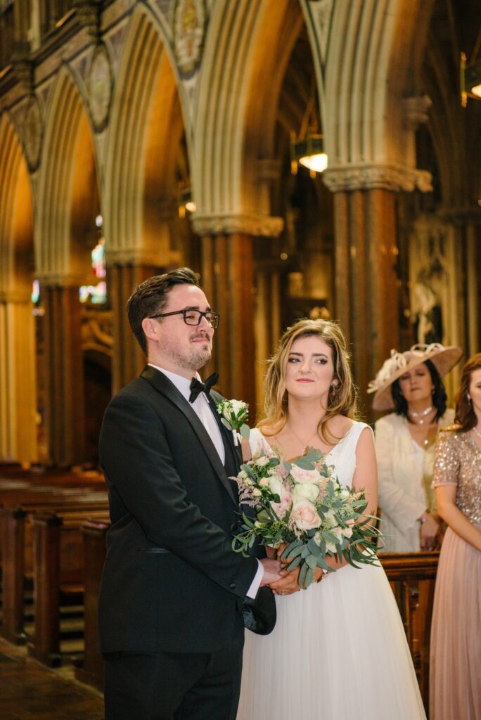 Groom crying during wedding ceremony with his bride at Farm Street Church in Mayfair