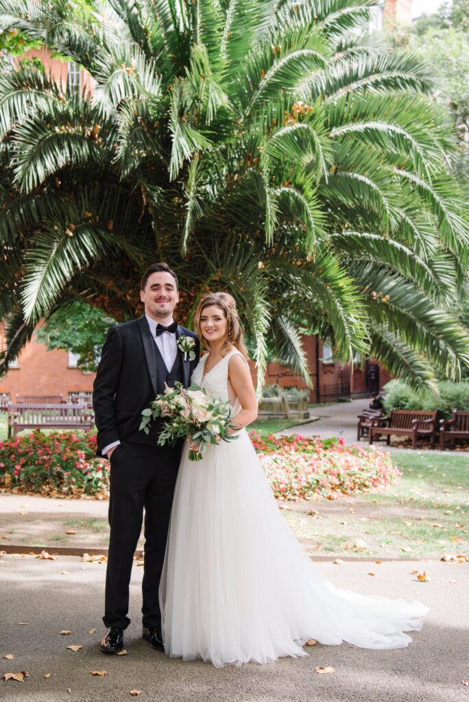 happy bride and groom in front of a tropical plant in Mount Street Gardens
