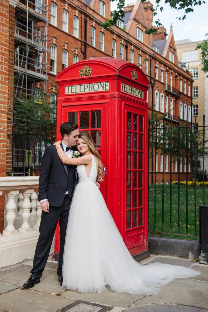 bride and groom in front of red telephone box during summer wedding in Mayfair