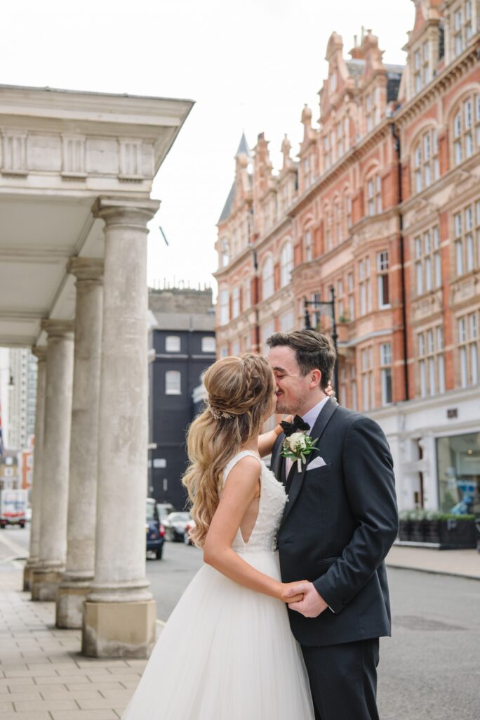 bride and groom kissing on a london street during summer wedding in Mayfair