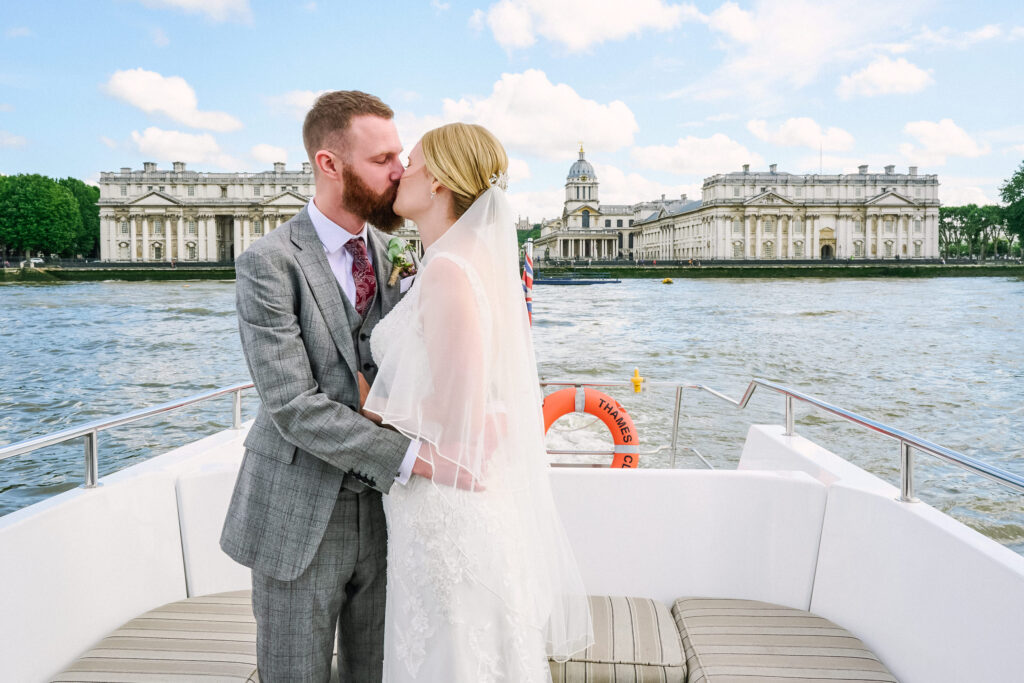 wedding couple kissing on a boat in front of the greenwich royal naval college