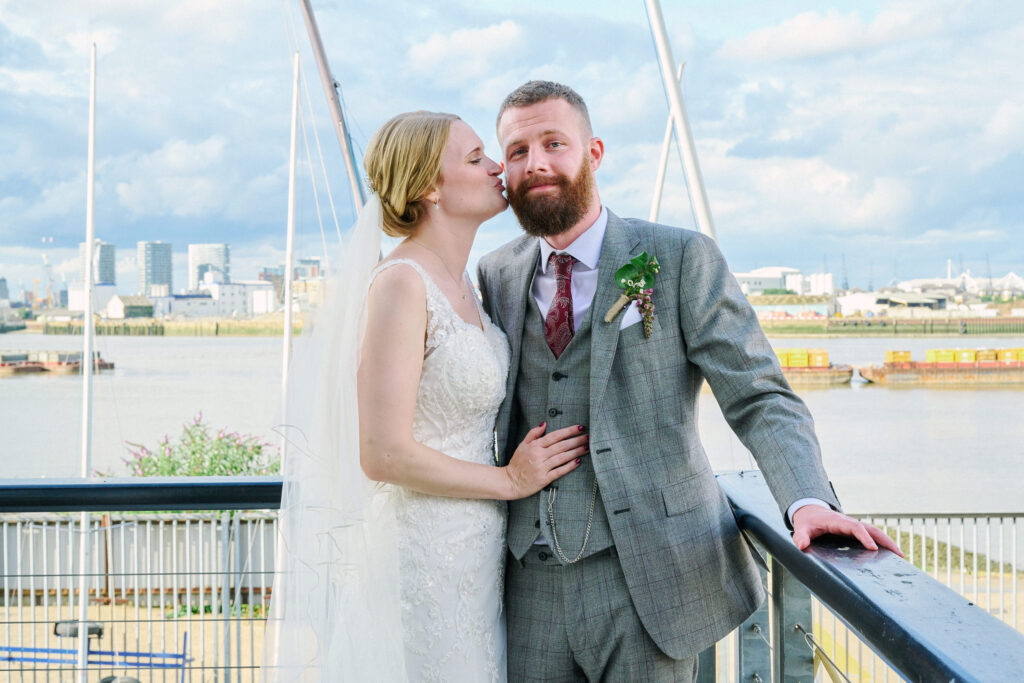 Wedding couple kissing on the sun deck with views of greenwich river behind