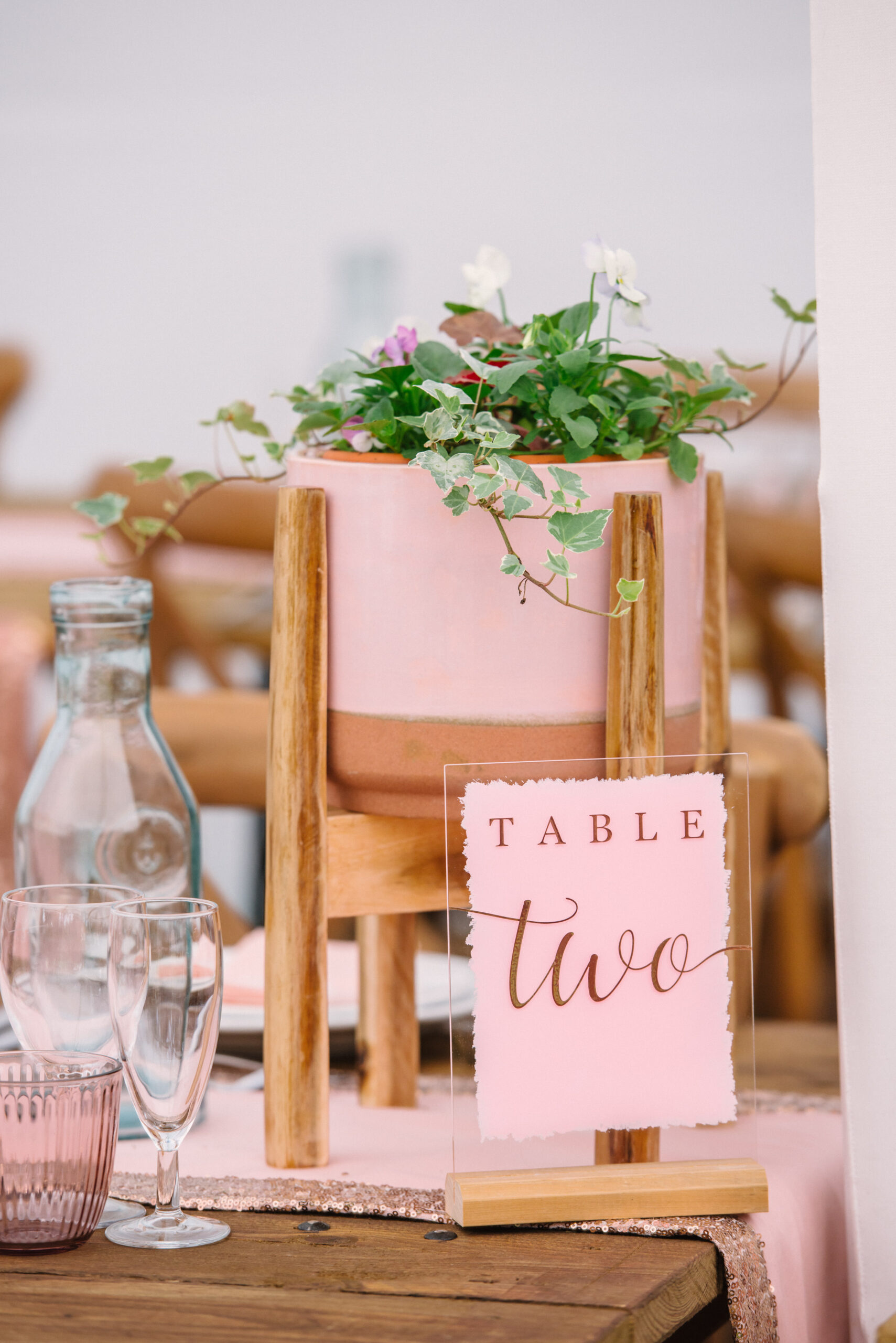 pink flower pot and table sign on rustic wooden wedding table