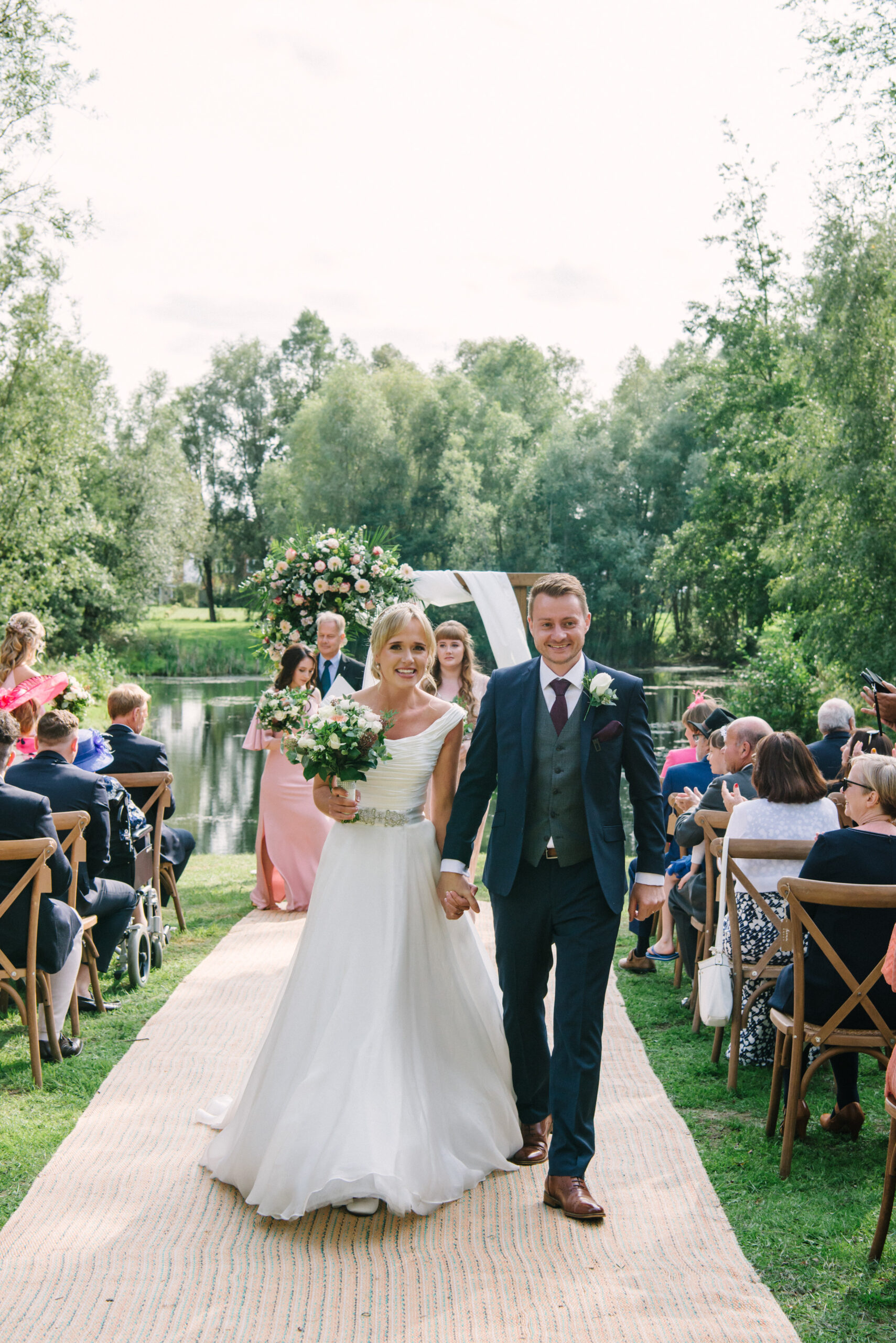 happy bride and groom walking down the aisle during outdoor summer wedding