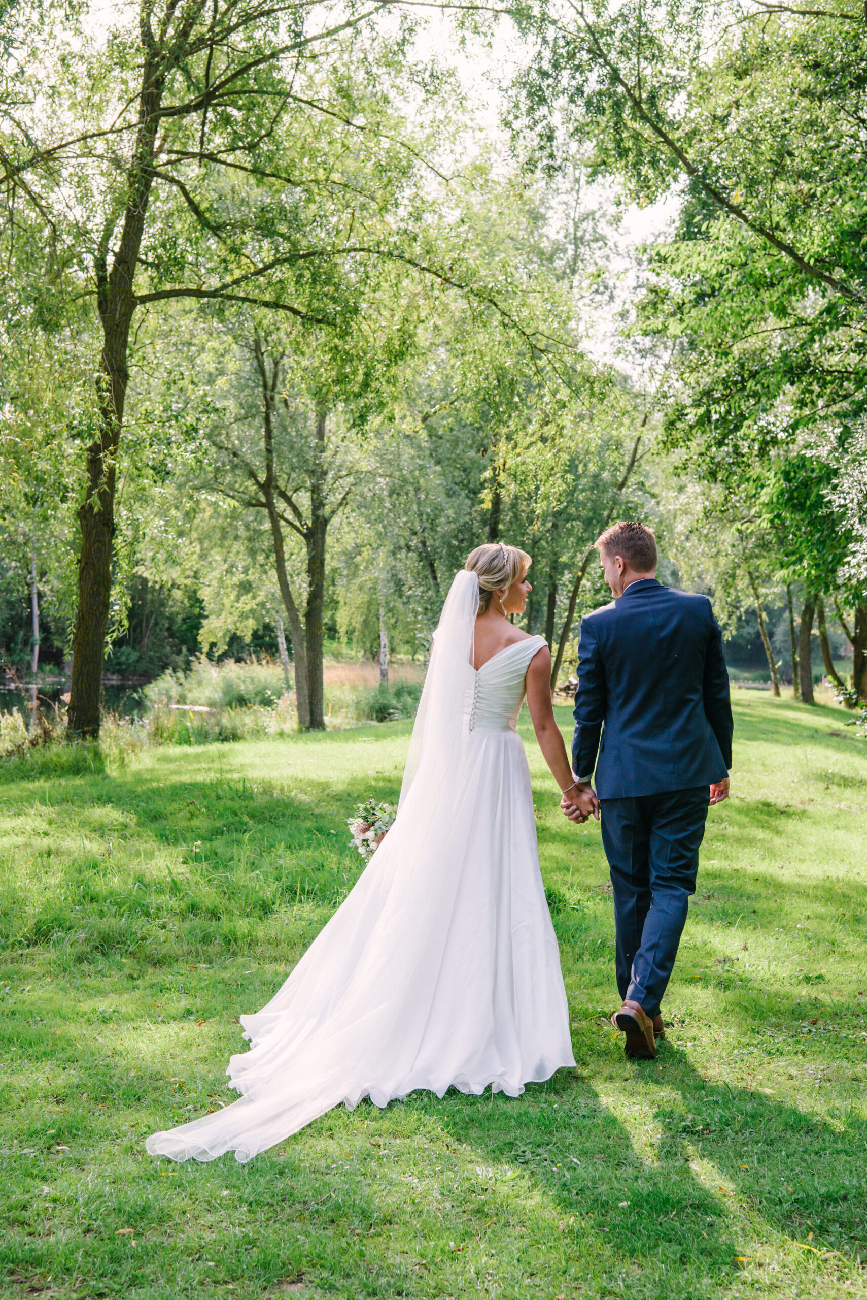 wedding couple walking through the grounds at Halliford Mere Lakes