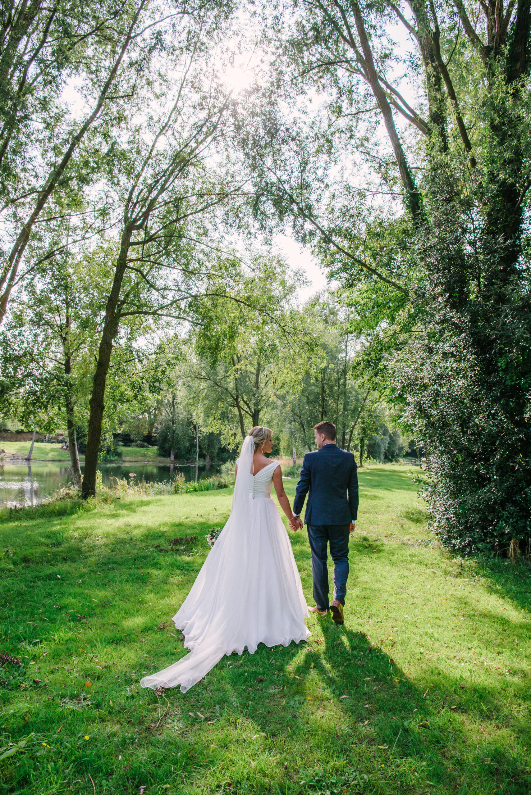 Bride and groom holding hands and walking together outside during summer wedding