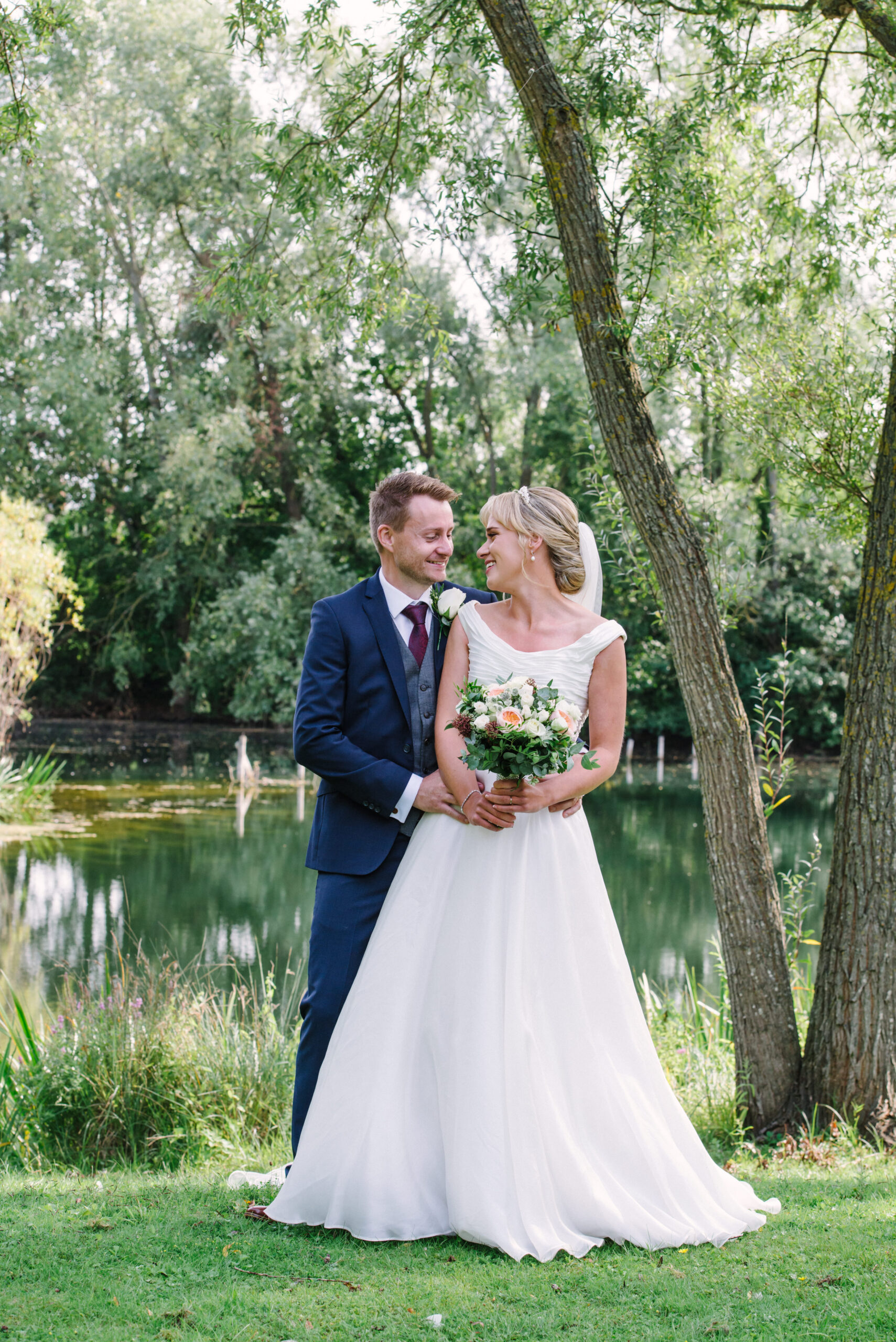 bride and groom in front of a lake during their outdoor surrey wedding
