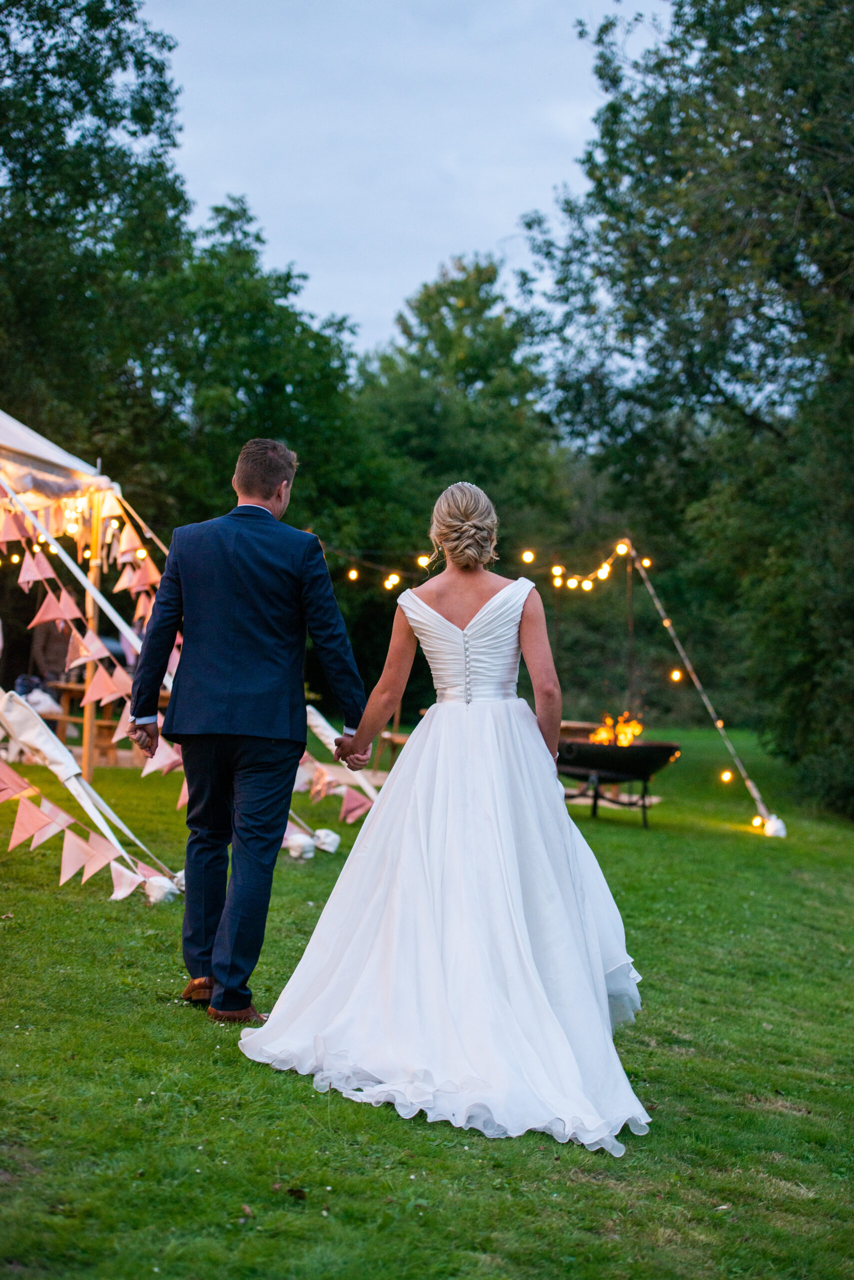 bride and groom walking away during evening reception at Halliford-Mere-Lakes