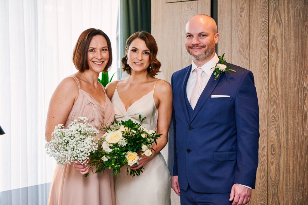 Bride stood with bridesmaid & brother in a London hotel room on her wedding day