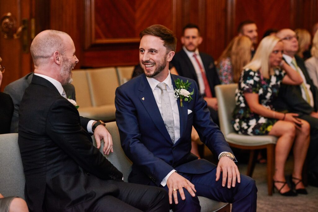Groom sat smiling in the Westminster ceremony room at Old Marylebone Town Hall