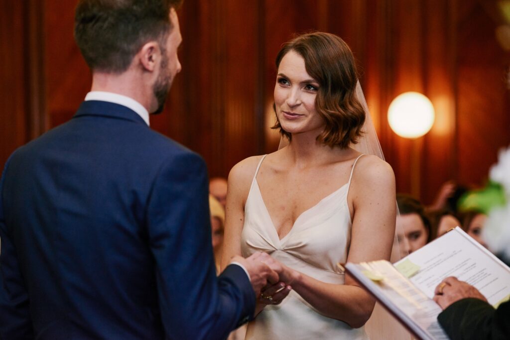 Bride smiling during her wedding ceremony in the Westminster room at Old Marylebone Town Hall