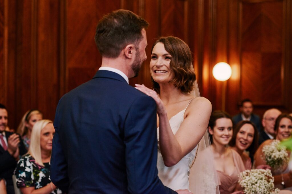Bride smiling during her wedding ceremony in the Westminster room at Old Marylebone Town Hall