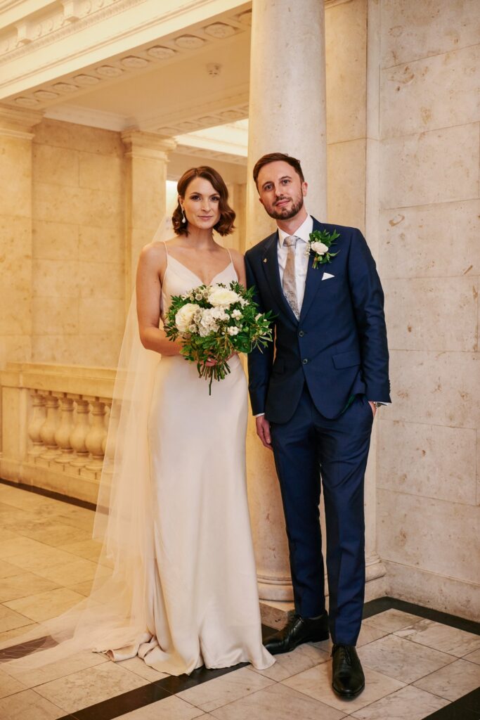 Bride & groom stood in the marble hallway at The Old Marylebone Town Hall wedding venue