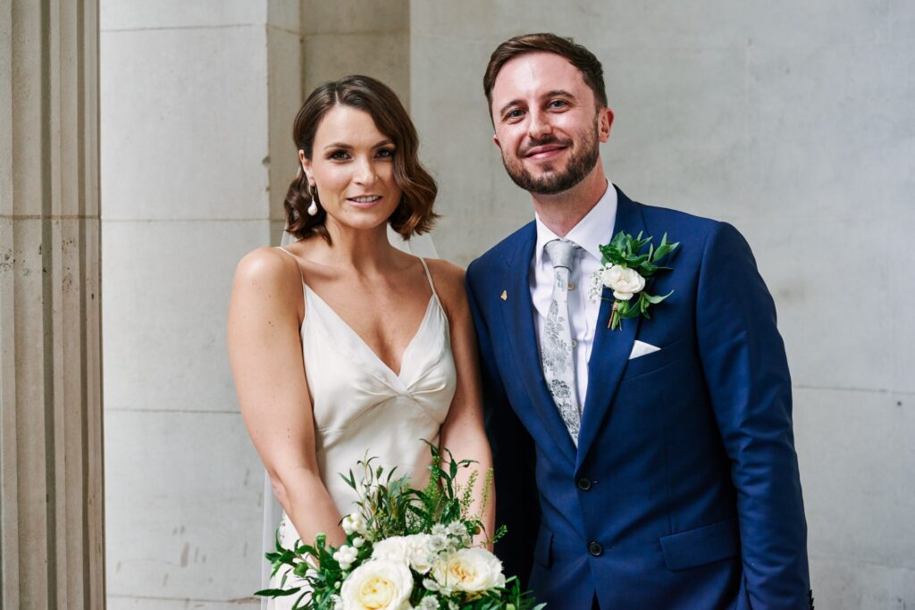 Bride & groom stood in front of  concrete at The Old Marylebone Town Hall