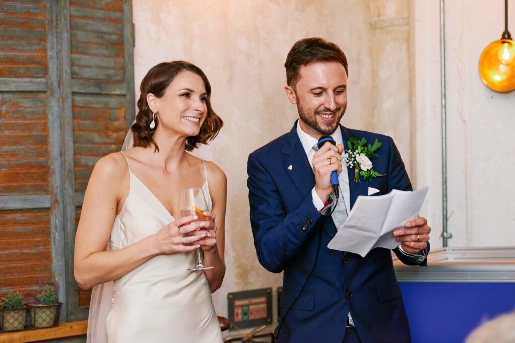 Bride & groom smiling during speeches in the Olive Grove at Union Street Café 