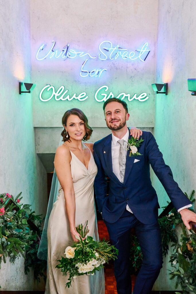 Wedding couple in front of a neon Union Street Café Olive Grove sign