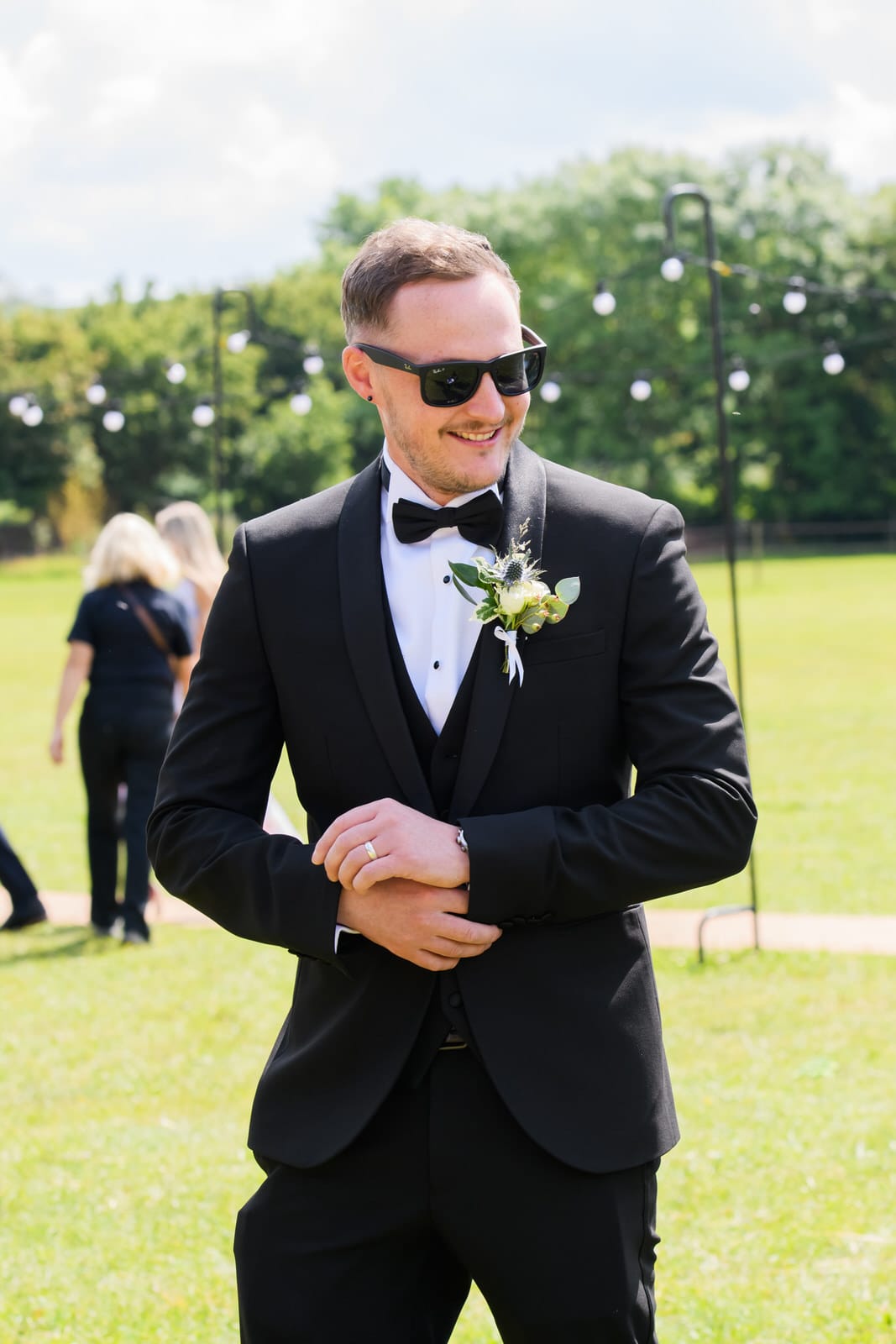Best man adjusting his suit outside at Overgrown Acres wedding venue