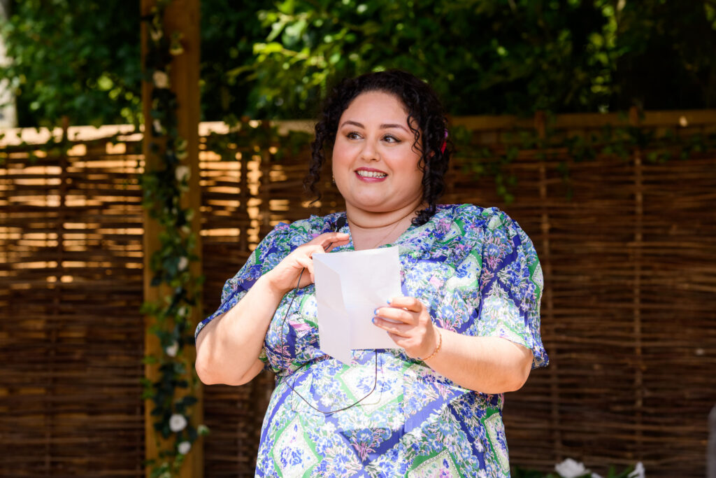 Women reading from paper during outdoor wedding ceremony under a pagoda