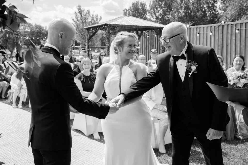 Dad giving away his daughter during outdoor wedding ceremony at Overgrown Acres