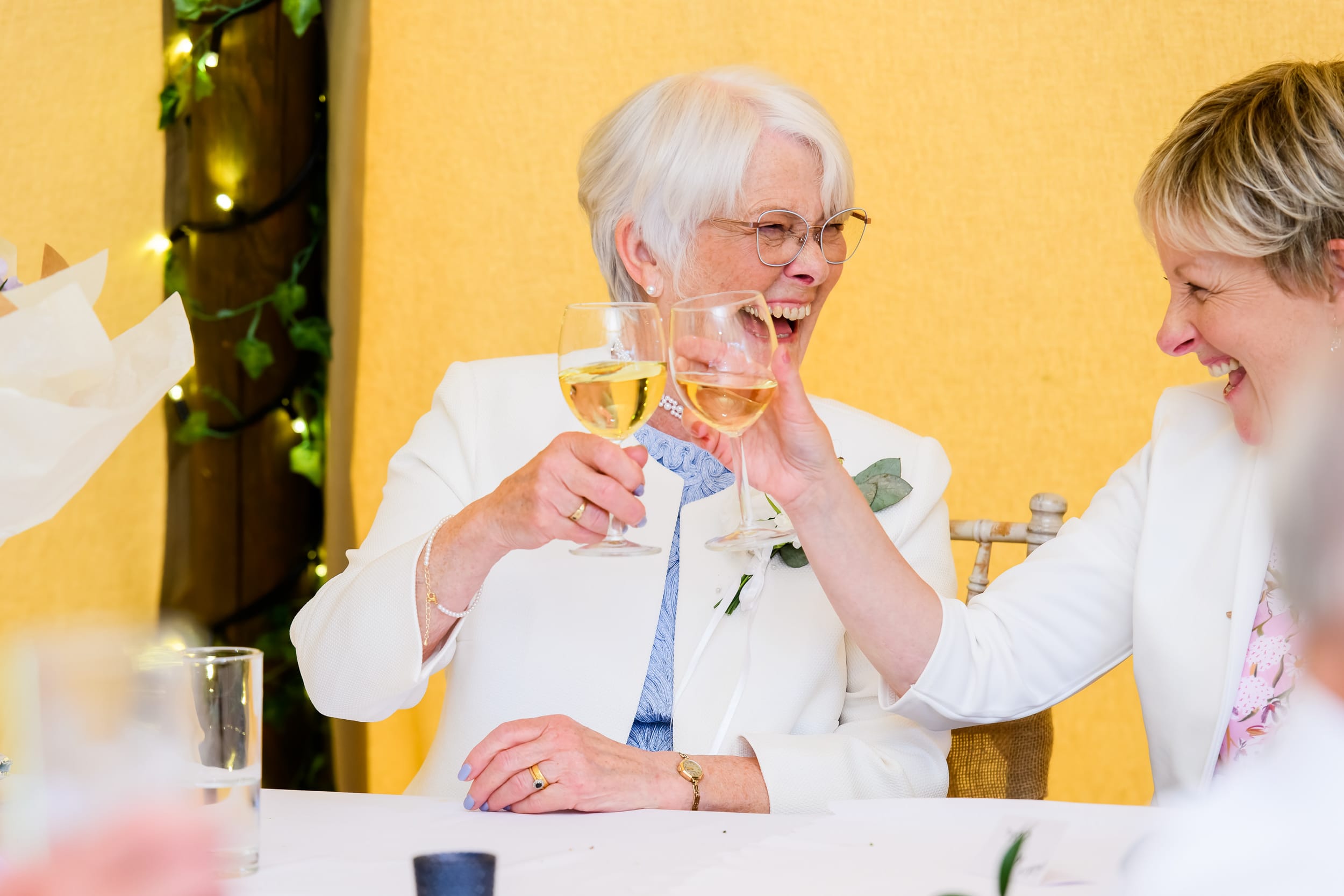 Brides mum laughing whilst holding up wine glass inside a festival tipi