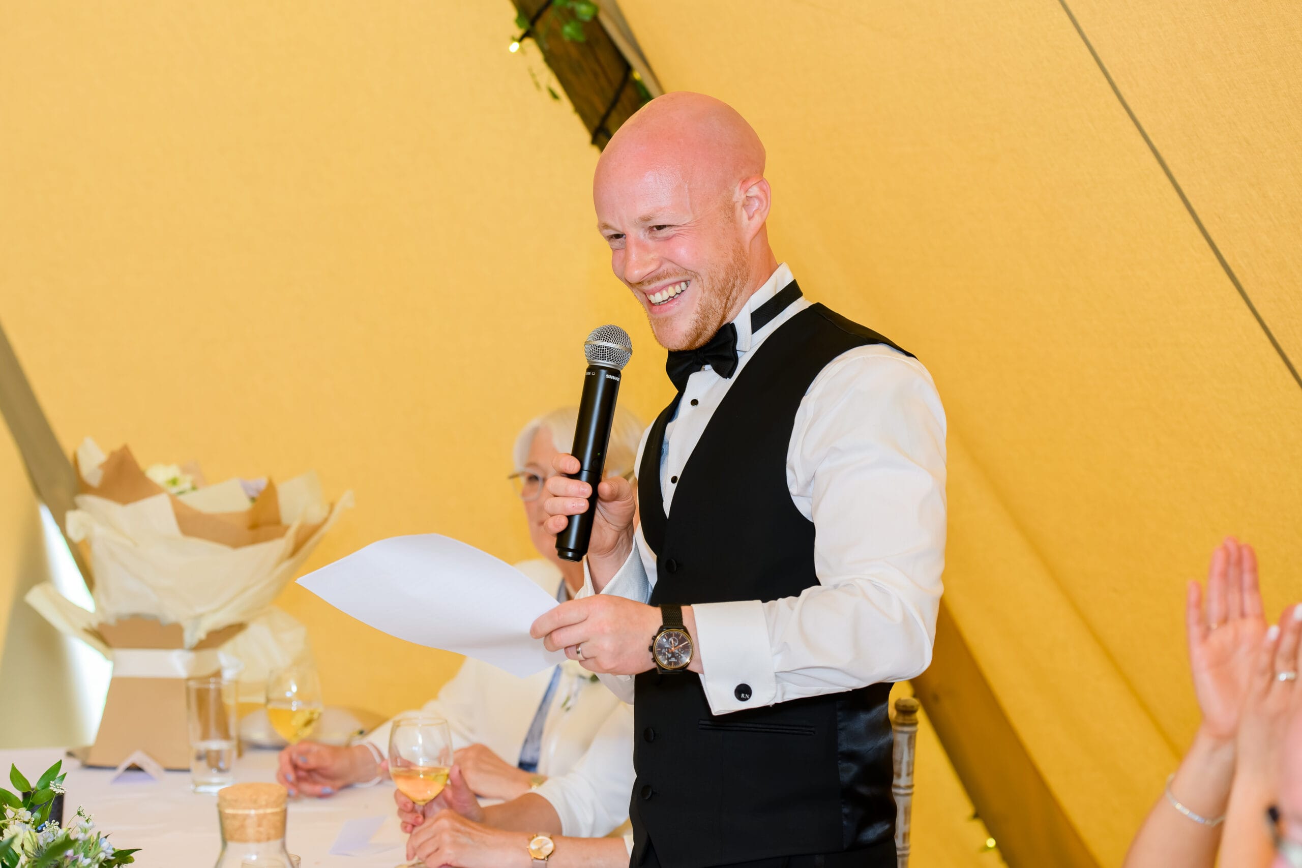 Groom laughing whilst giving a speech during tipi wedding reception