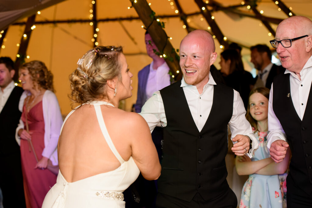 Groom having fun on the dance floor inside overgrown acres wedding tipi