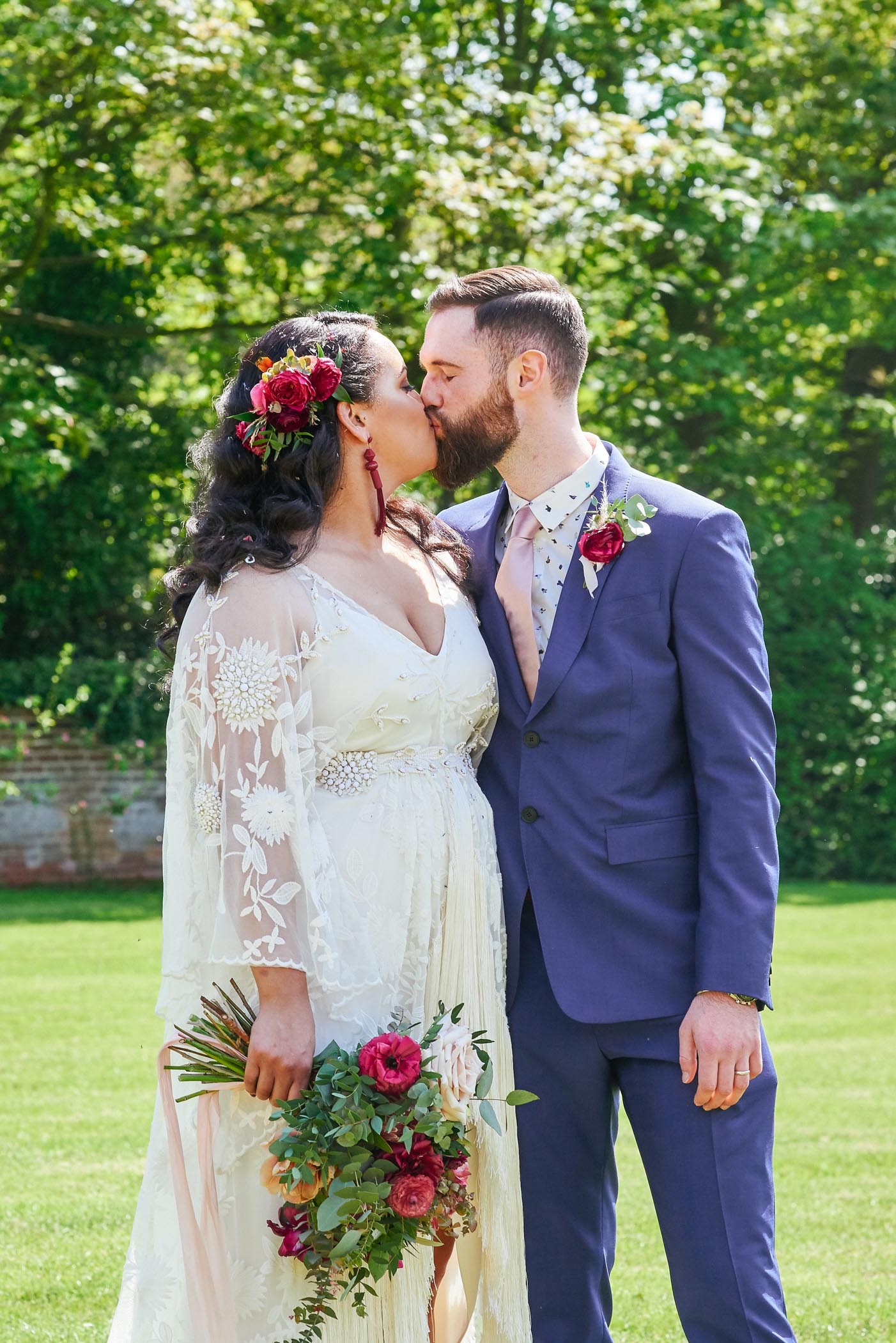 Bohemian bride and groom kissing outside in the walled garden