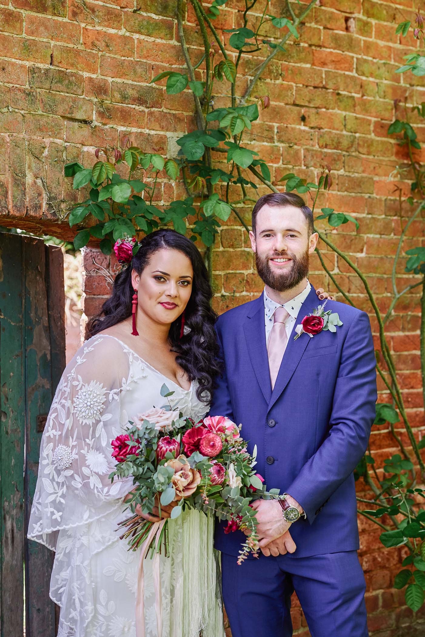Bohemian bride and groom in front of green door at The Walled Garden in Beeston