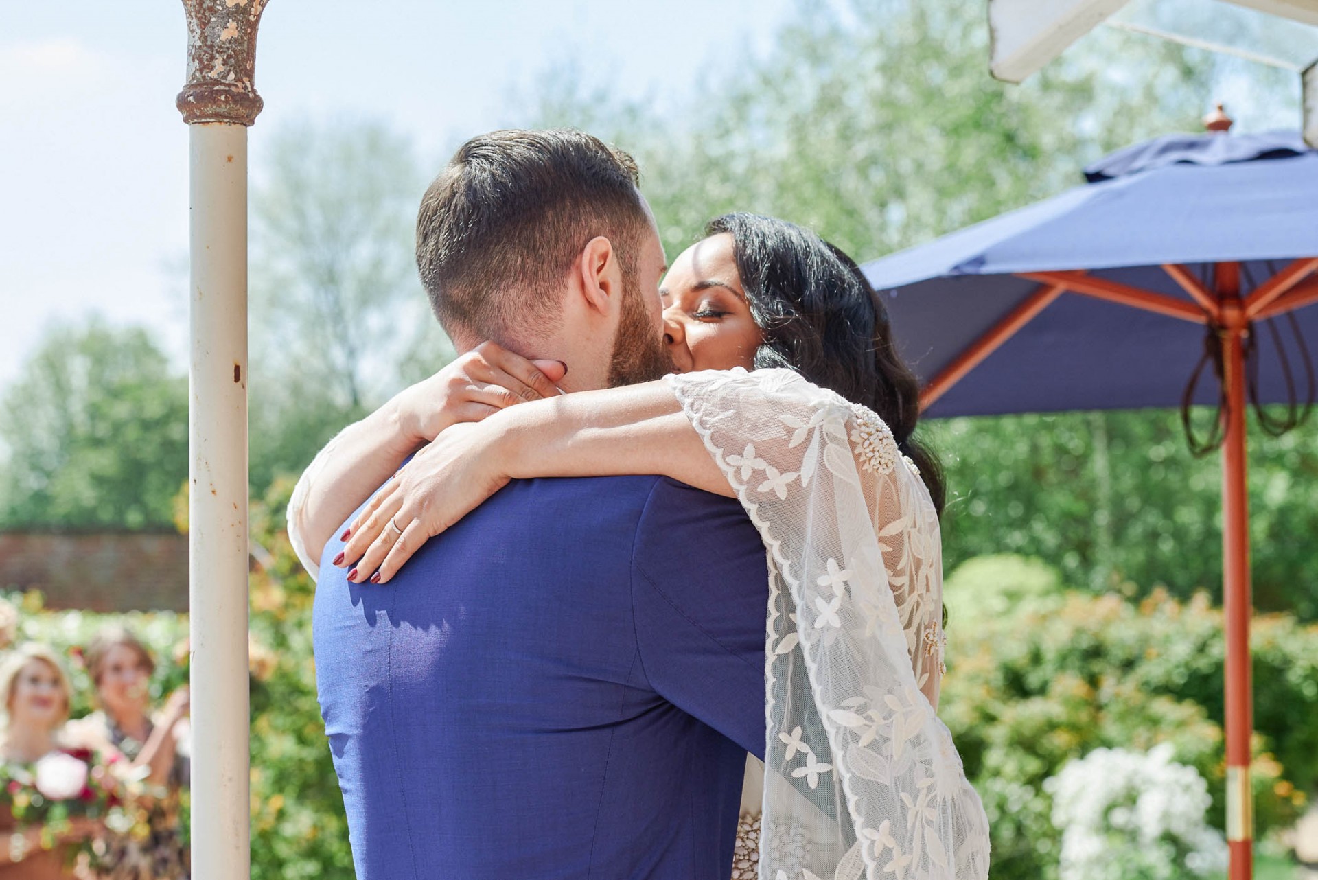 Bohemian bride and groom kissing during outdoor wedding ceremony at the Walled Garden in Beeston.
