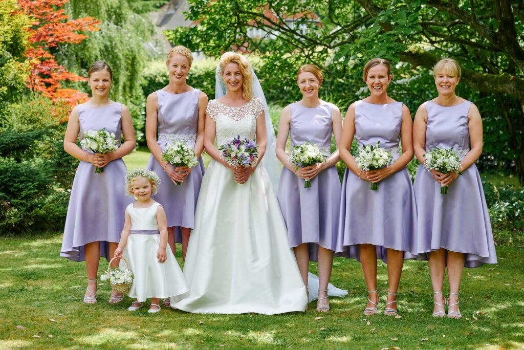 bridesmaids wearing lilc smiling in the grounds at Ridge Farm wedding venue