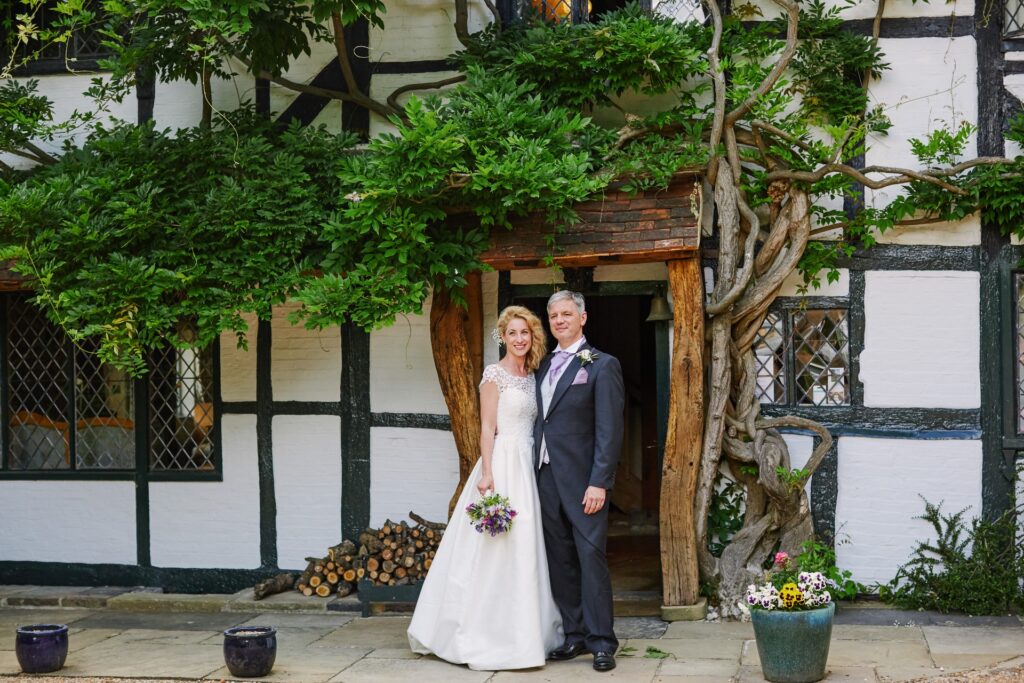 bride and groom smiling in front of the farmhouse at Ridge Farm