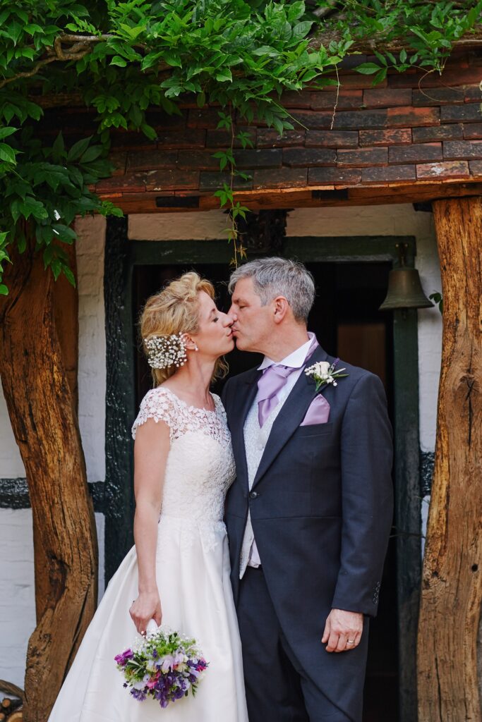 bride and groom kissing in front of the farmhouse door at Ridge Farm