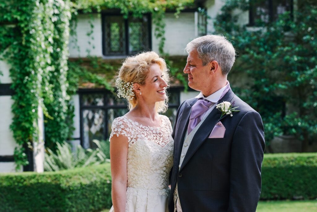 bride and groom smiling in front of the old farmhouse at Ridge Farm
