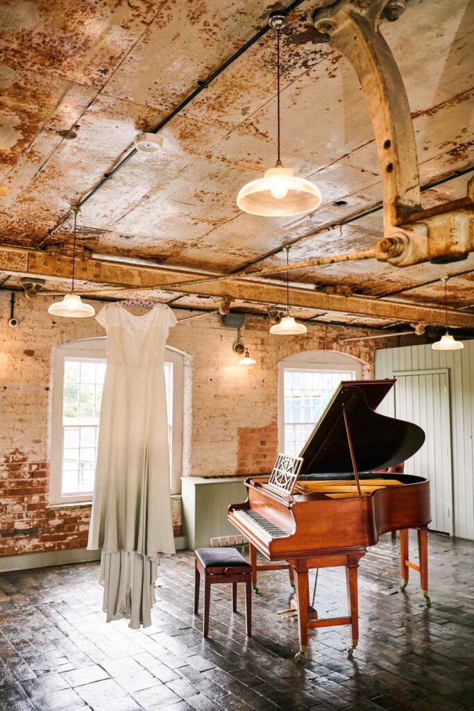 dip dyed wedding dress hung up in an industrial metal room next to a piano 