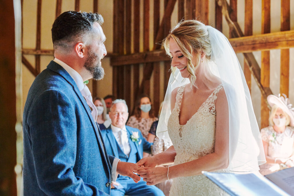 Bride & groom exchanging wedding rings during their stokes farm barn wedding