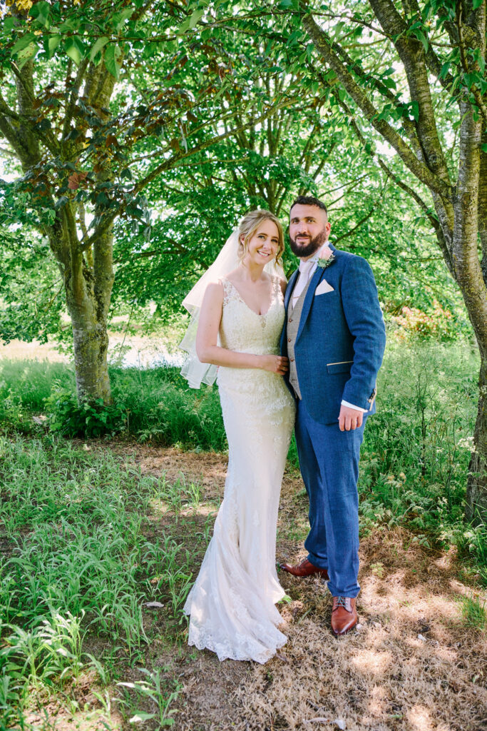 wedding couple stood under trees during their wedding photography shoot
