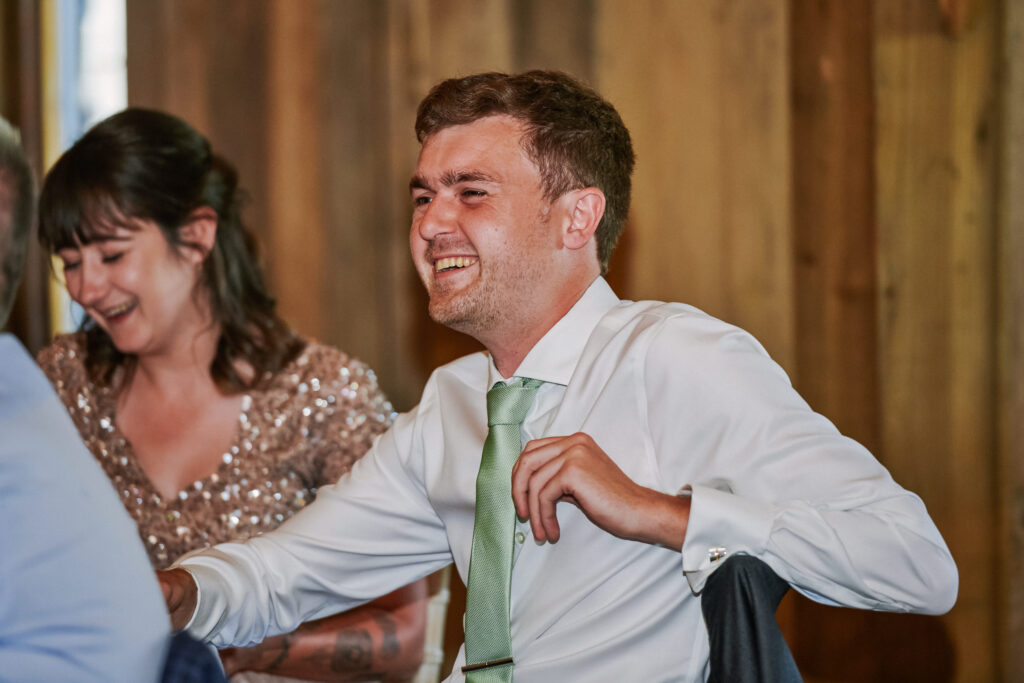wedding guest laughing whilst sat in rustic wedding room